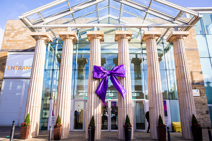 Columns at entrance to Hall M at HCC dressed with big purple ribbon bow